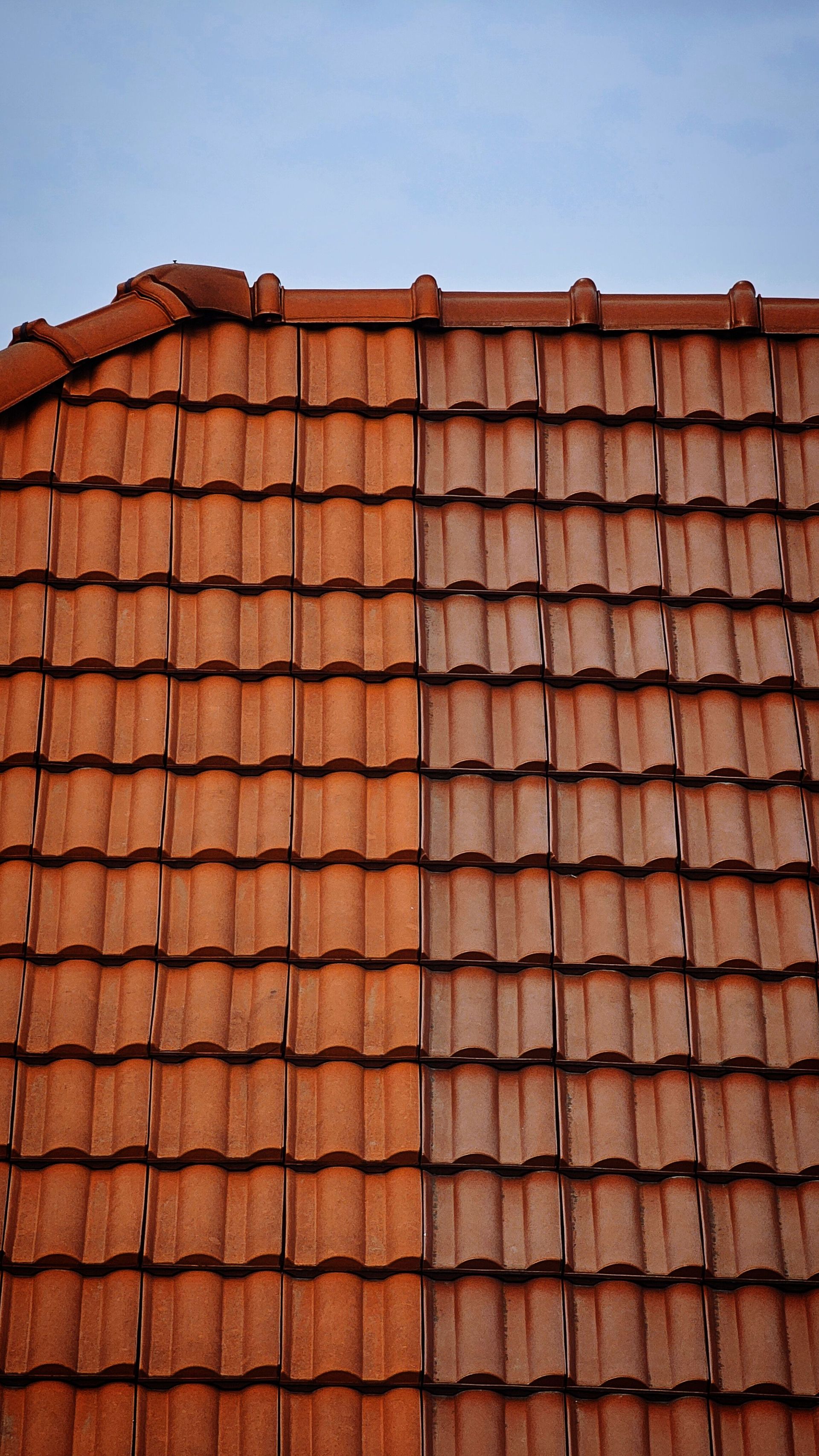 Detailed view of classic red clay roof tiles under a clear blue sky.